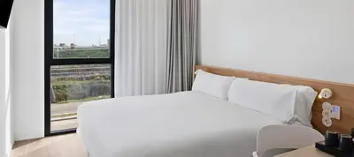 a bedroom with a white bed and a large window at B&B HOTEL Valencia Alcàsser in Alcácer