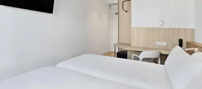 a bedroom with a white bed and a desk at B&B HOTEL Valencia Alcàsser in Alcácer