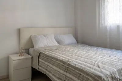 a white bedroom with a bed and a night stand at Conectado y Moderno, ven a VLC! in Valencia