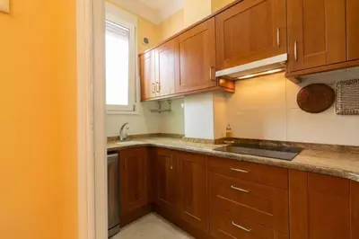 a kitchen with wooden cabinets and a sink and a window at Central Apartment Sleeps 6 Fast Wi-Fi 2 Bathrooms in Valencia