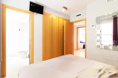 a bedroom with a bed and a tv on a wall at Global Vacacional, Moderno y práctico adosado en Puerto de Sagunto in Puerto de Sagunto