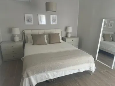 a white bedroom with a bed and two night stands at Ca Maruja in Cullera