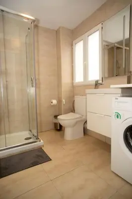 a bathroom with a toilet and a shower and a washing machine at Apartamento acogedor frente a Torres de Serrano in Valencia