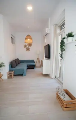 a living room with a blue couch and a tv at Apartamento acogedor frente a Torres de Serrano in Valencia