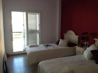 a bedroom with two beds and a window with a door at Chalet frente al Mar in Cullera