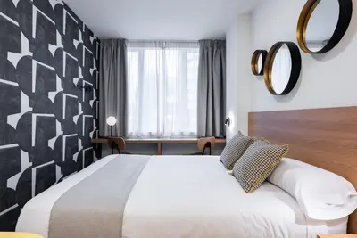 a hotel room with a bed and a mirror at Smartr Valencia Turia in Valencia