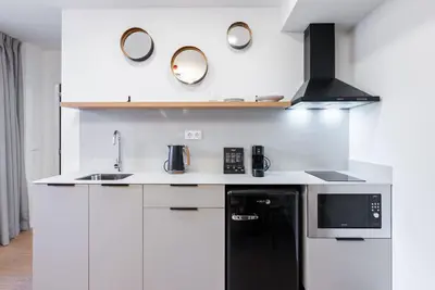 a kitchen with white cabinets and a black refrigerator at Smartr Valencia Turia in Valencia