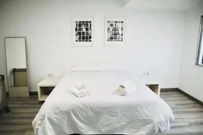 a white bed in a white room with two desks at Big Flat Ruzafa in Valencia