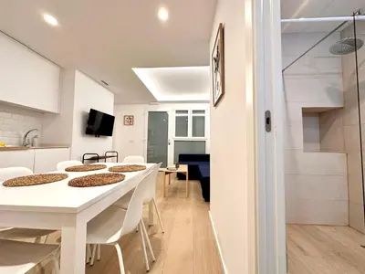 a kitchen and dining room with white tables and chairs at Apartamento Hierros VLC in Valencia