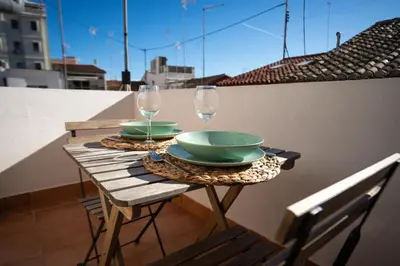 a table with two glasses and plates on a balcony at Apto 3 P Ferrandis in Valencia