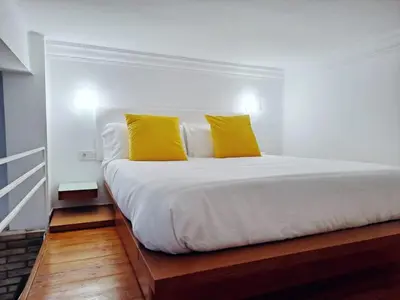 a white bed with two yellow pillows on it at Loft DobleAltura Escalante in Valencia