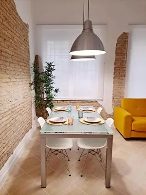 a dining room with a table and a yellow couch at Loft DobleAltura Escalante in Valencia
