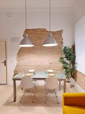 a dining room with a table and chairs and a brick wall at Loft DobleAltura Escalante in Valencia
