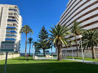 a park with palm trees in front of tall buildings at El Prado - Primera Línea Playa Cullera in Valencia
