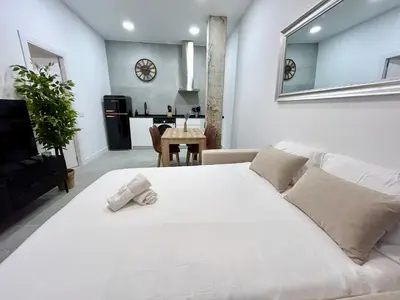 a bedroom with a white bed and a living room at Convenient, Charming Apartment 15 Mins from City Center in Valencia