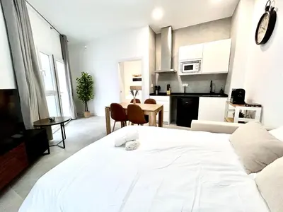 a bedroom with a large white bed and a kitchen at Strategic Stay-Unlock Valencia's Best-Kept Secret in Valencia