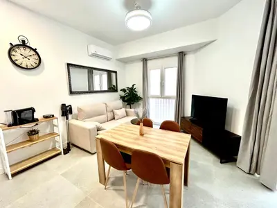a living room with a table and a clock on the wall at Strategic Stay-Unlock Valencia's Best-Kept Secret in Valencia