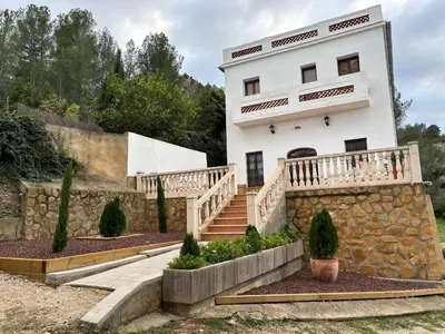 a white house with a stone wall and stairs at Paraiso Natural Unico -Villa Cueva Turche in Valencia