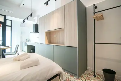 a bedroom with a white bed and a kitchen at District Key - Valencia, O Arocena 1 in Valencia