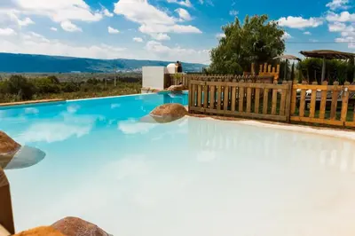 a swimming pool with blue water and a wooden fence at La villa de Naomi in Chella