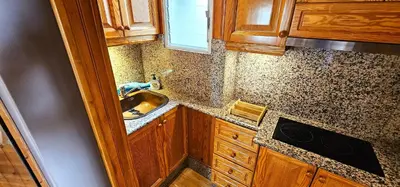 a small kitchen with a sink and wooden cabinets at Vacansis Atico Loft El Mercat in Valencia