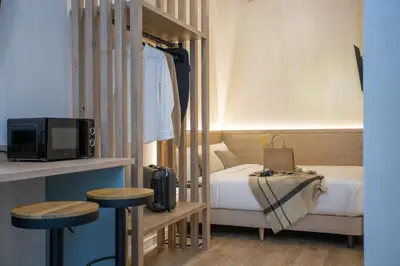 a small bedroom with a bed and two stools at Nomad Haux Mestalla Room 101 in Valencia