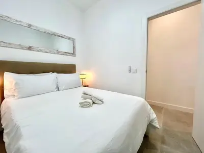 a white bed with two towels on top of it at Valencia Comfort Stay Near Metro, 2 Bed, 1 Bath in Valencia