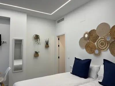 a bedroom with white walls and a bed with blue pillows at Apartments Vent de Vela in Valencia