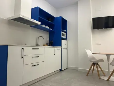a kitchen with white cabinets and a blue accent wall at Apartments Vent de Vela in Valencia