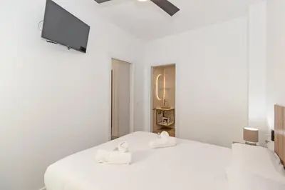 a white bedroom with a bed and a flat screen tv at GuestReady - A lovely studio in la Saidia Valencia in Valencia
