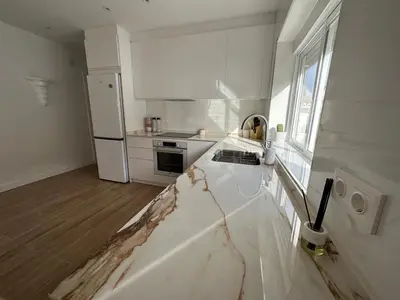 a white kitchen with a marble counter top at La Casita in La Eliana