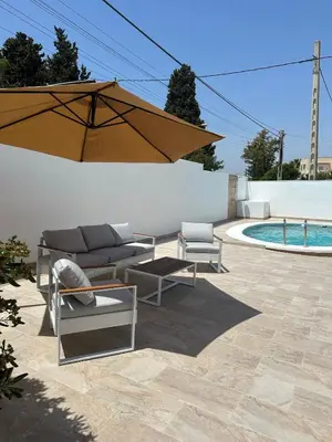 a patio with a couch and an umbrella and a pool at La Casita in La Eliana