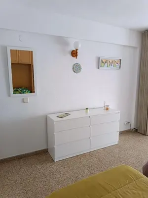 a white bedroom with a dresser and a mirror at Estudio Playa Cullera in Cullera