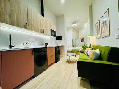 a living room with a green couch and a kitchen at Stylish Design Studio in Valencia in Valencia