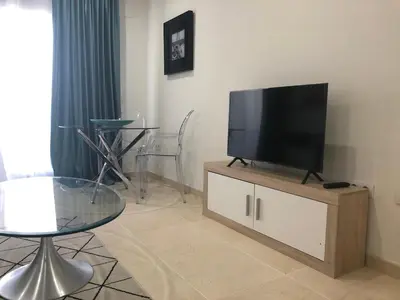a living room with a flat screen tv on a cabinet at Direct view to the beach , Parking , Terraza in Valencia