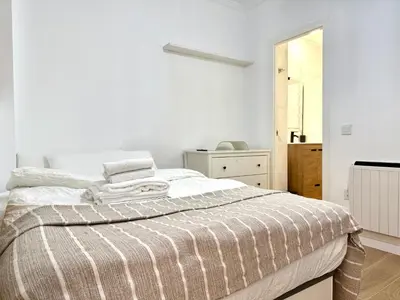 a white bedroom with a bed with a striped blanket at Reinapart Cabanyal in Valencia