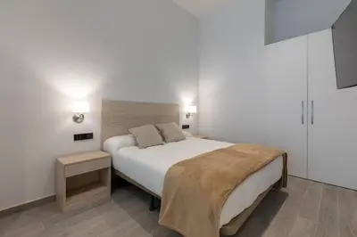 a bedroom with a large white bed and two tables at Apartamento 1º nuevo cerca playa in Valencia