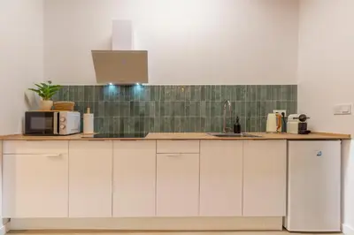 a kitchen with white cabinets and a green tiled wall at Paradise Suite - Cómodo y acogedor - Conectado con Aeropuerto, Playa y Centro in Valencia