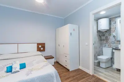 a bedroom with a white bed and a bathroom at Precioso estudio en la playa norte de Valencia in Puebla de Farnals