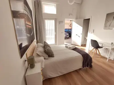a bedroom with a bed and a desk and a window at District Key - Valencia, Plaza del Cedro in Valencia