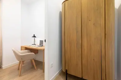 a wooden cabinet next to a desk and a chair at Travel Habitat Peset Aleixandre Apartments in Valencia