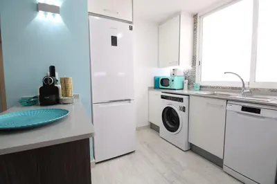 a kitchen with white cabinets and a washer and dryer at Vacansis Apartamento Malvarrosa in Valencia