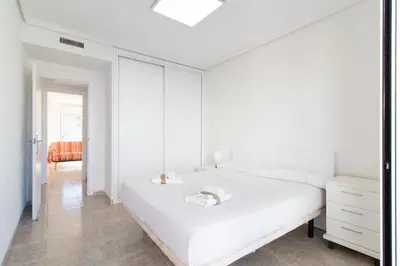 a white bedroom with a bed and a dresser at Global Vacacional, Apartamento en primera linea de playa en Canet de Berenguer in Canet de Berenguer