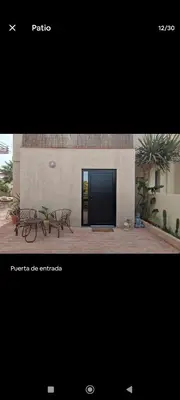 a picture of a building with two benches and a black door at Casa con piscina junto al mar in El Perellonet