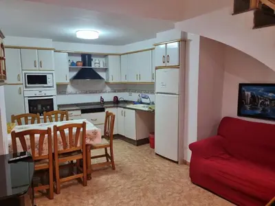 a kitchen and dining room with a table and a red couch at Casa Amando in Chulilla