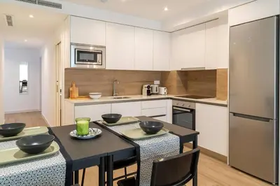 a kitchen with white cabinets and a black table with chairs at Central Market Deluxe Apartments in Valencia