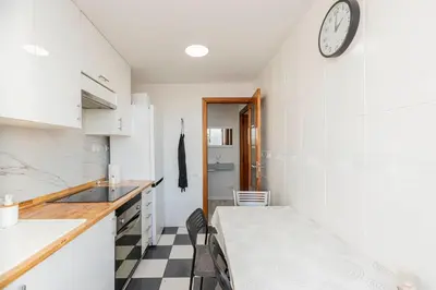 a kitchen with a table and a clock on the wall at Apartamento en el Cabanyal enfrente de la Marina Real in Valencia
