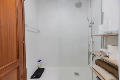 a bathroom with white walls and a shelf with towels at Apartamento en el Cabanyal enfrente de la Marina Real in Valencia