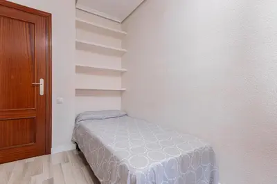 a small bedroom with a bed and a wooden door at Apartamento en el Cabanyal enfrente de la Marina Real in Valencia