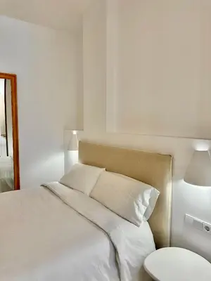 a white bed with white sheets and pillows at Anelsa Suites Serranos 1 in Valencia